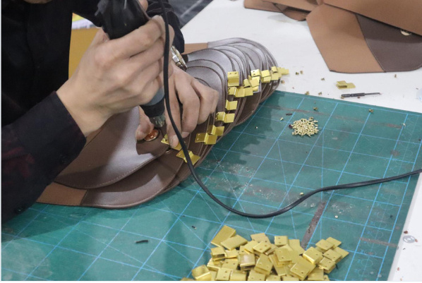 Hand assembly of metal hardware on bag components at Changrong